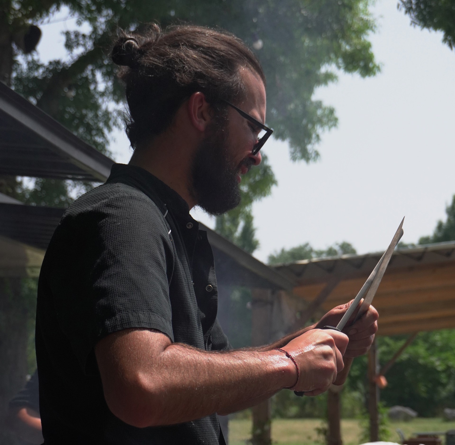 Portrait du chef de la Guinguette du Peyrat, concentré sur la préparation en plein air. - réalisé par Agence Kulte