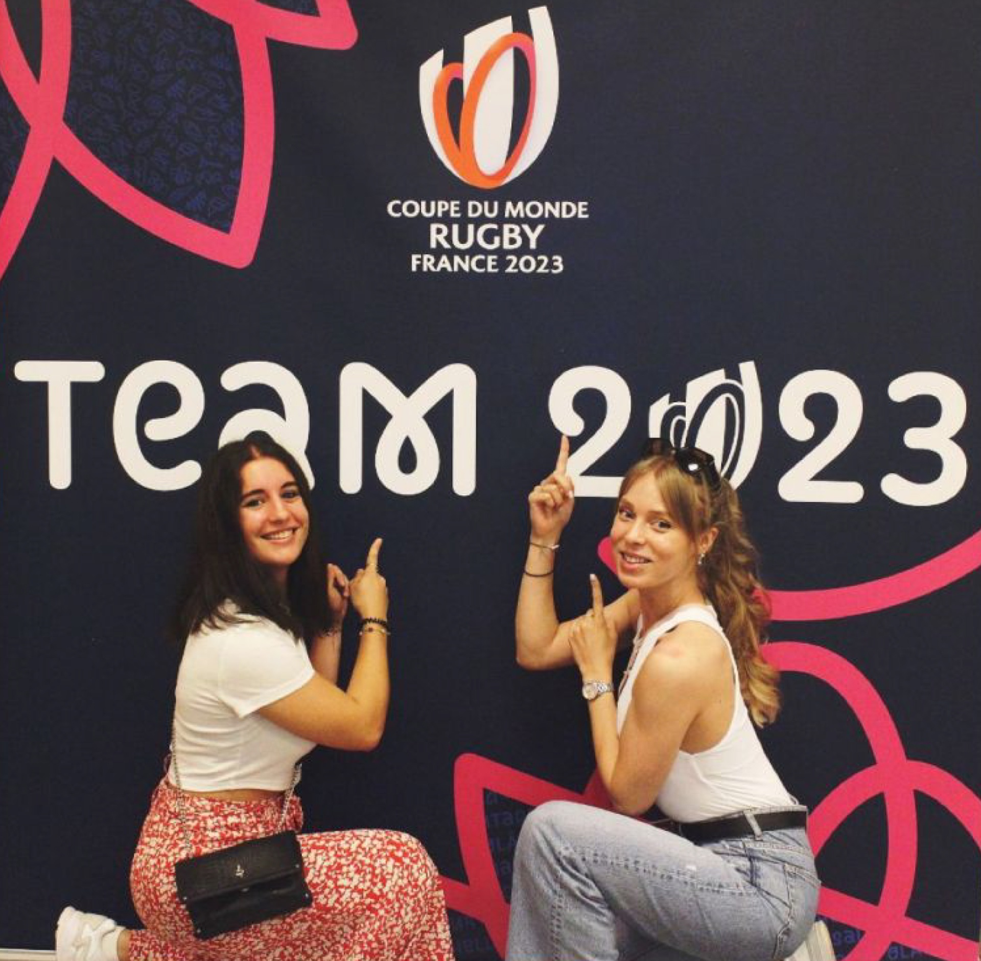 Deux volontaires posant devant le mur officiel Team 2023 — Coupe du Monde Rugby France 2023 - réalisé par Agence Kulte